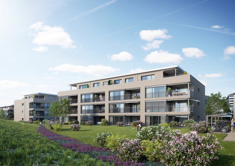 Die modernen Wohngebäude von Kokon Immobilien verfügen über große Balkone und bieten einen Blick auf eine Grünanlage mit blühenden Sträuchern und einem Fahrradständer, alles unter einem blauen Himmel mit vereinzelten Wolken.