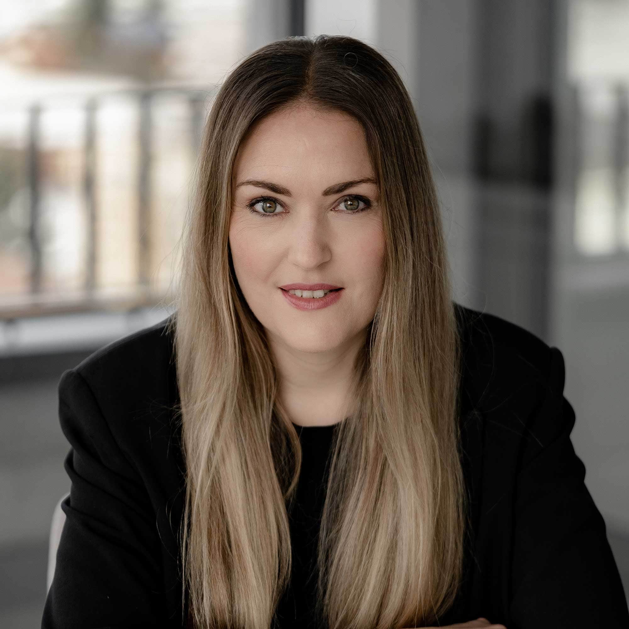 Eine Frau mit langen Haaren und einer schwarzen Jacke.